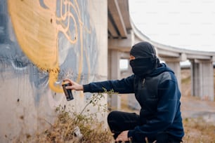Un homme vêtu d’un sweat à capuche noir peignant un mur