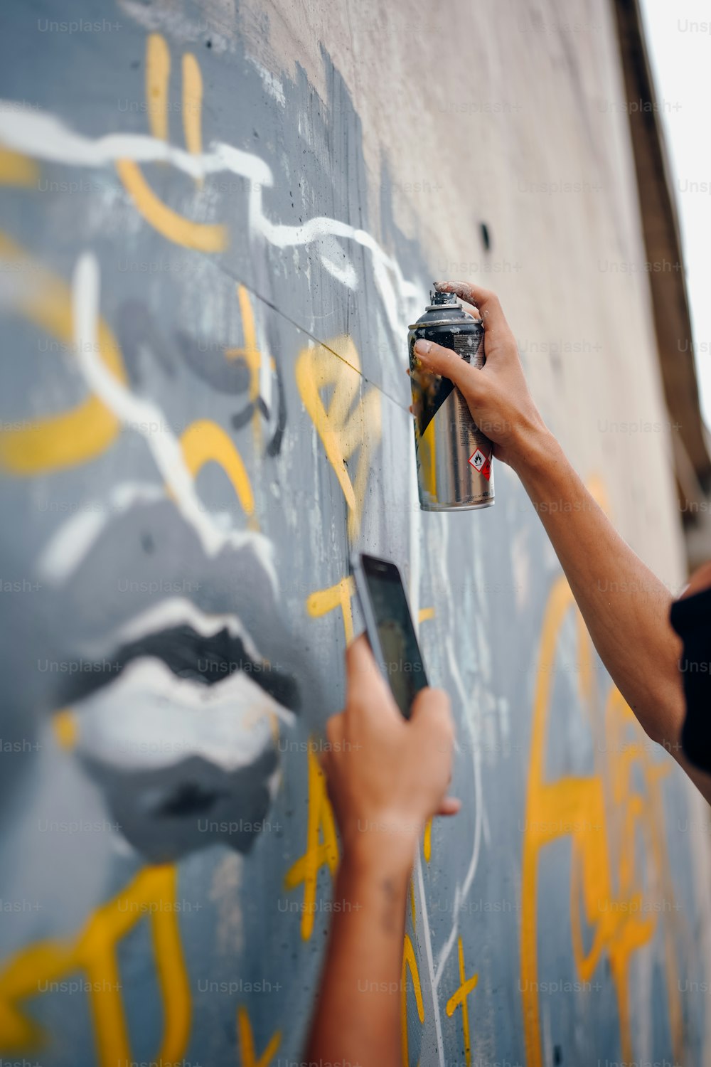 a person spray painting a wall with yellow and white paint