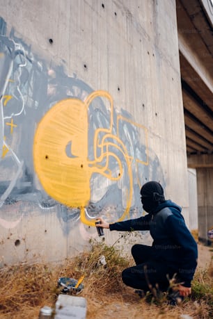 a man kneeling down in front of a graffiti covered wall