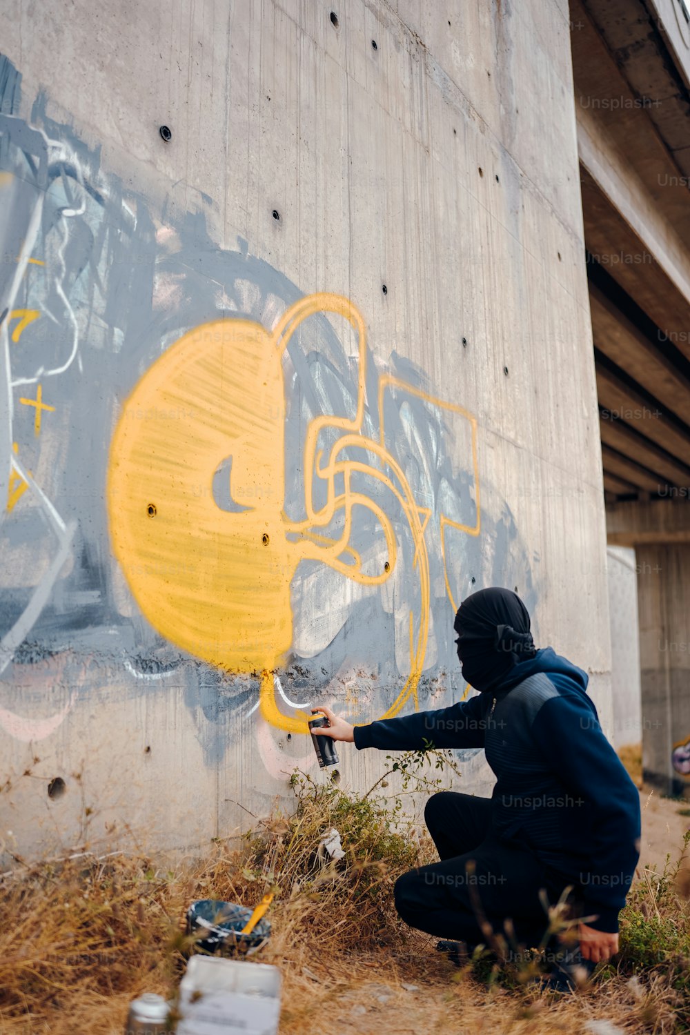 a man kneeling down in front of a graffiti covered wall