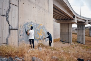 a couple of people standing next to a wall