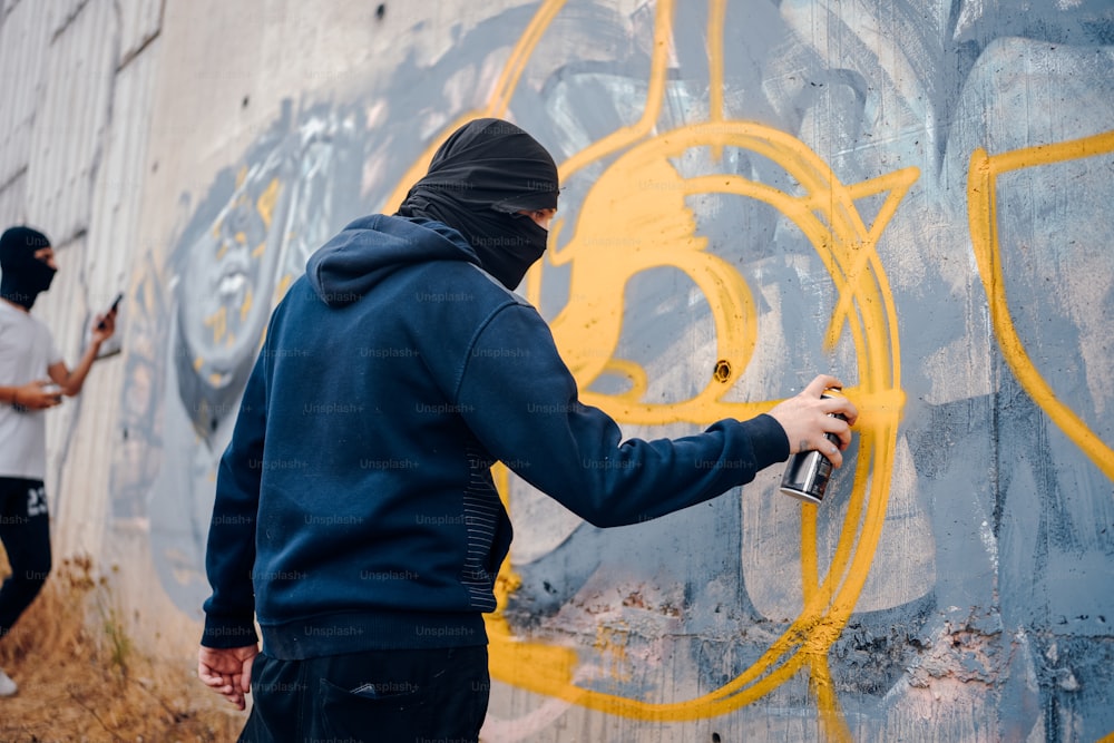 um homem spray pintando uma parede com grafite amarelo