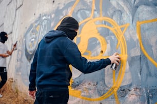a man spray painting a wall with yellow graffiti