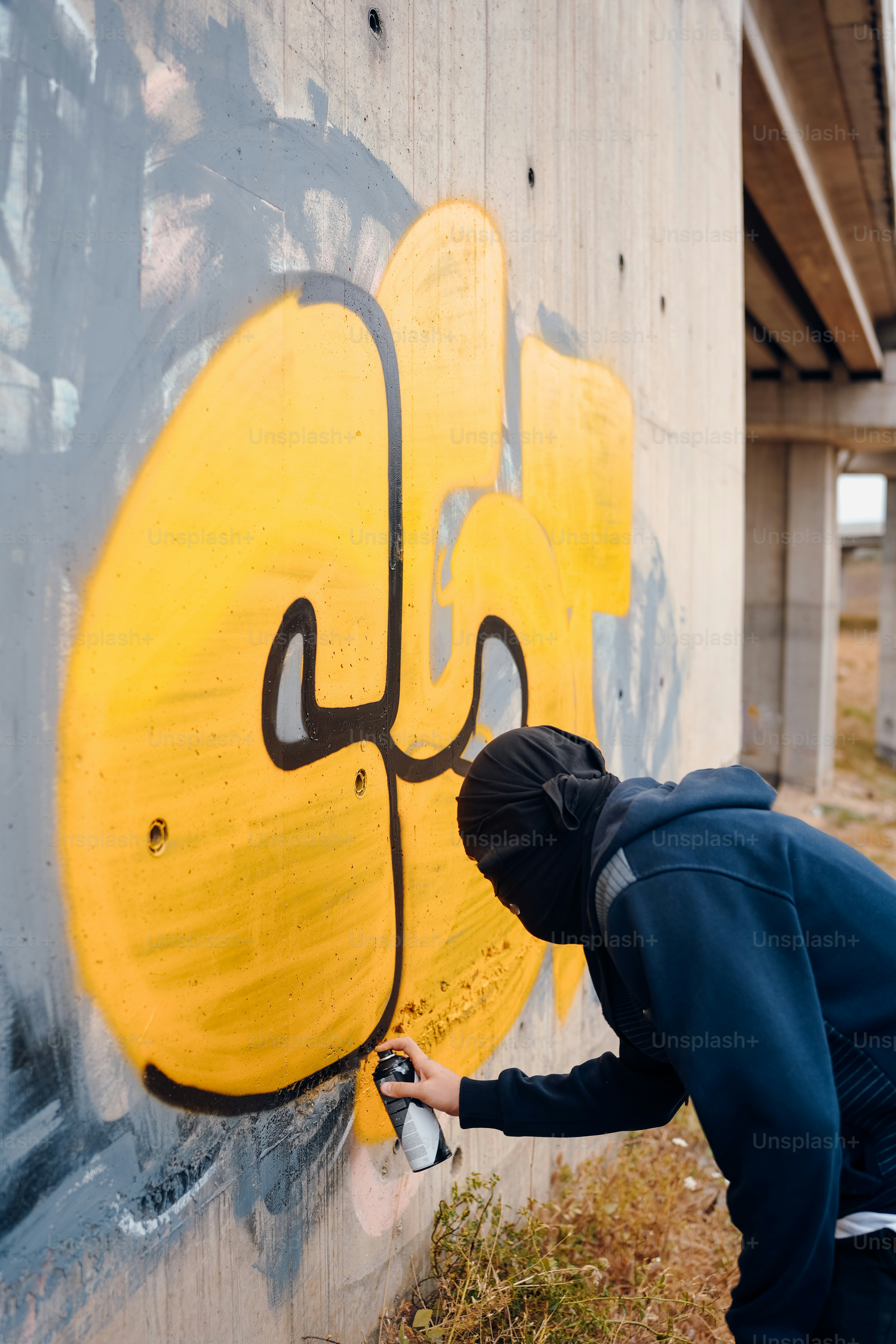 a man spray painting a wall with yellow and black graffiti