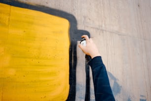 한 사람이 노란색과 검은색 벽을 칠하고 있다