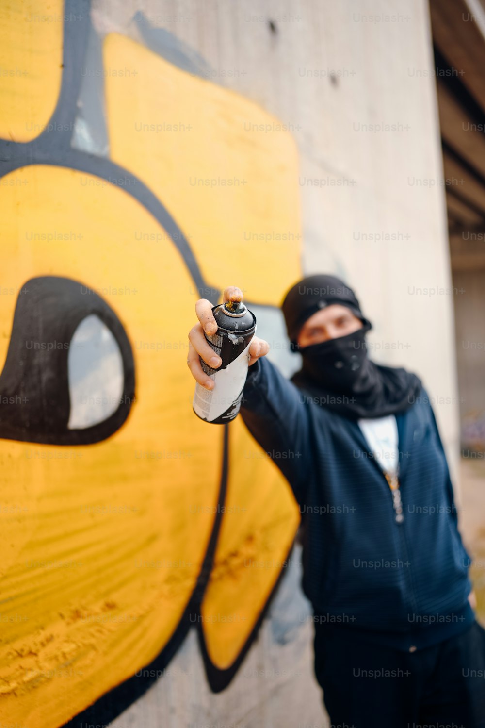 a man holding a spray bottle in front of a graffiti wall