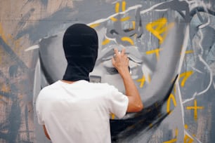 Um homem de camiseta branca está pintando grafite em uma parede