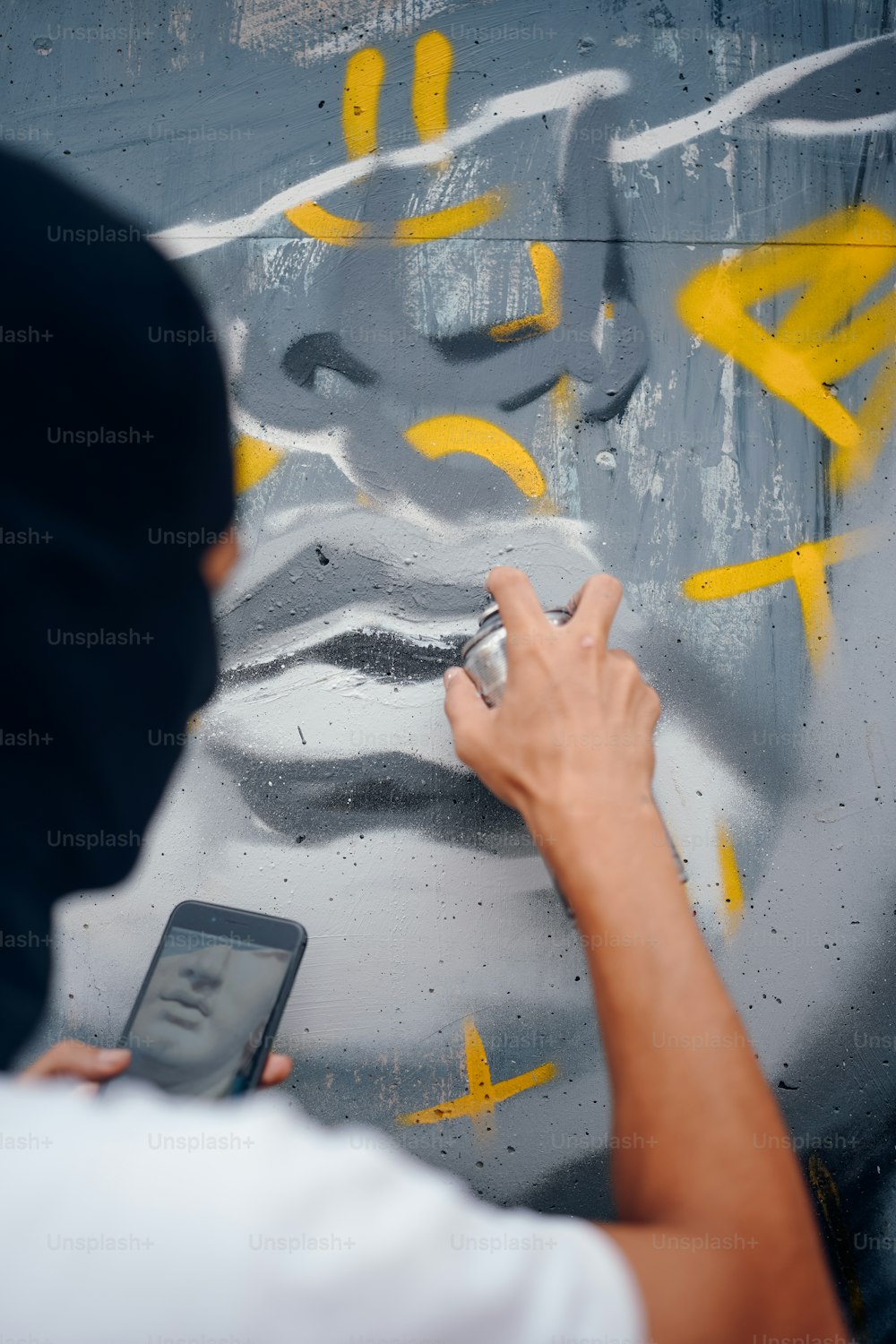 a man writing on a wall with a cell phone
