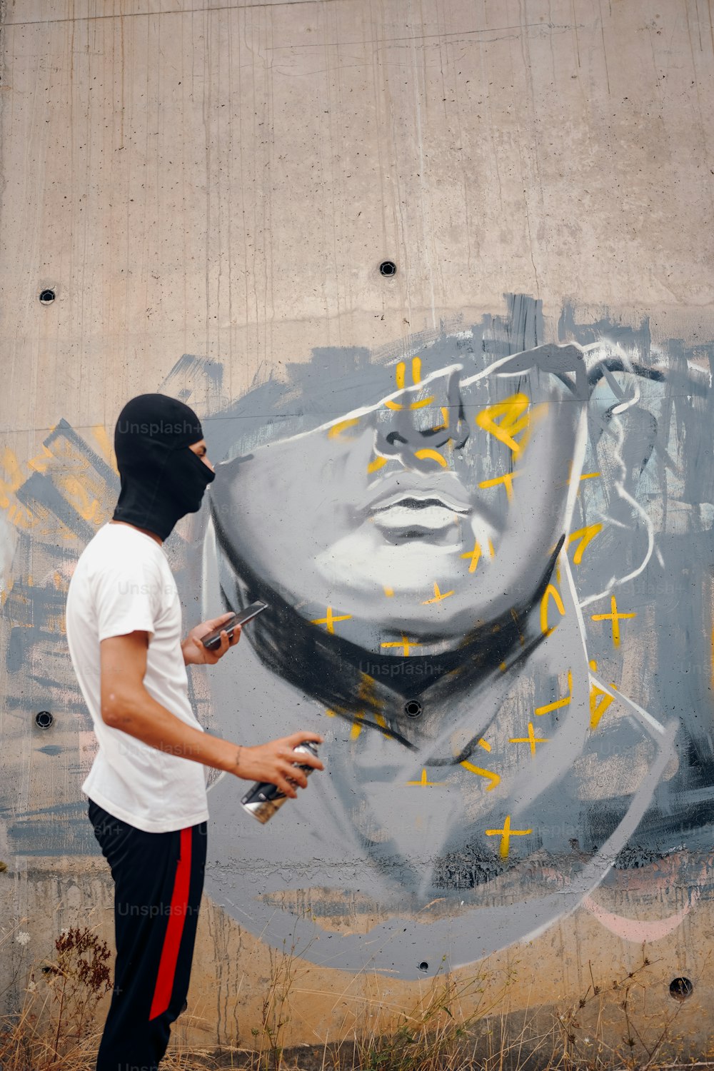 um homem spray pintando um mural em uma parede