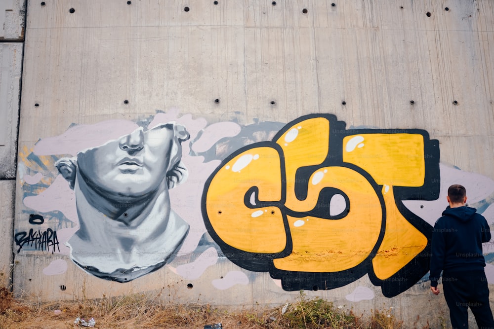 a man standing in front of a wall with graffiti on it