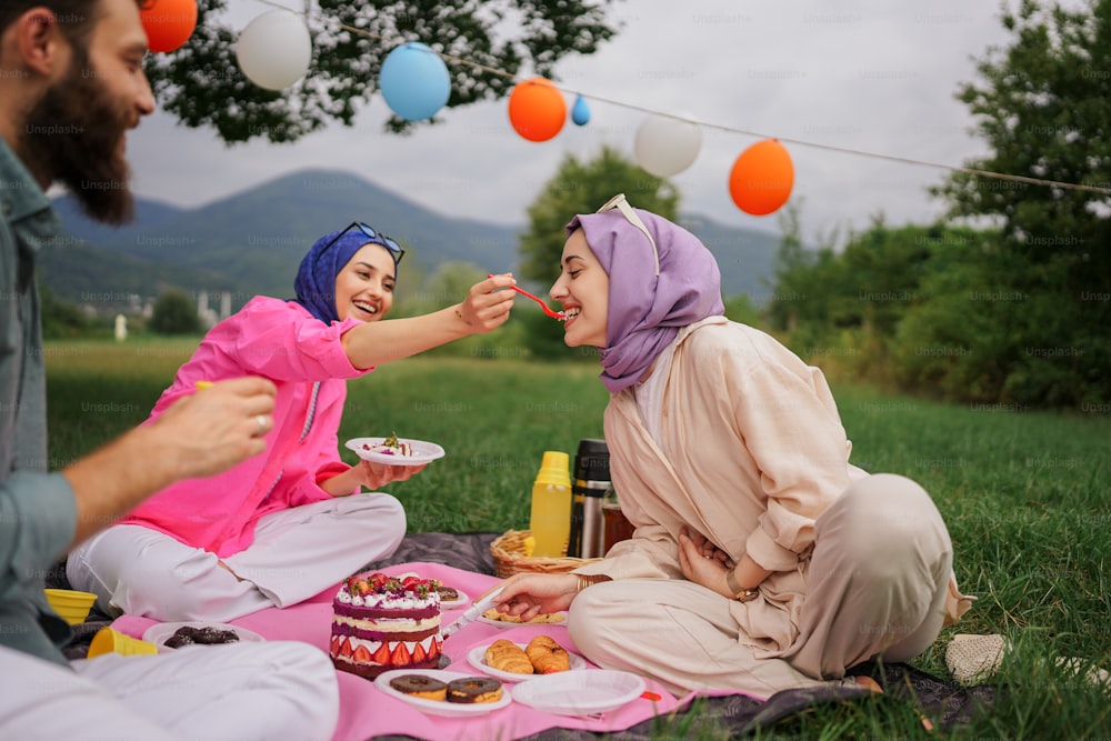 a couple of women sitting on top of a grass covered field