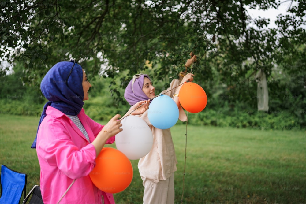 Un par de mujeres de pie una al lado de la otra sosteniendo globos