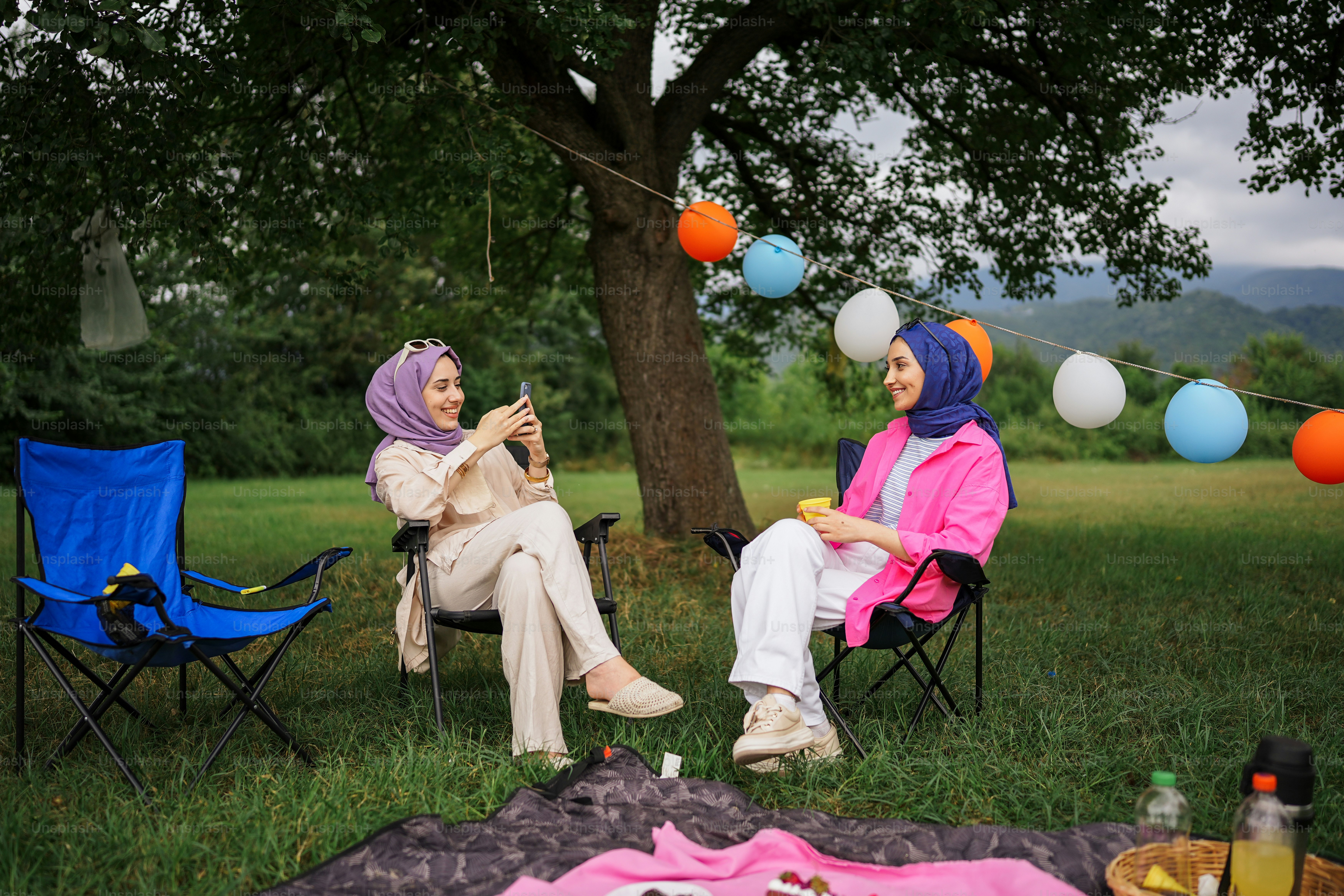 Dua wanita duduk di kursi rumput berbicara satu sama lain