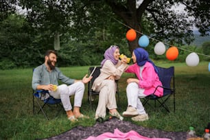 a group of people sitting in lawn chairs under a tree