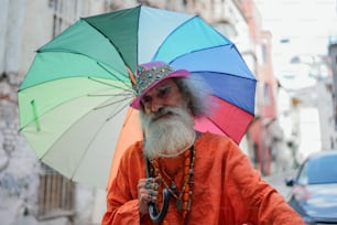 Un hombre con una larga barba y un paraguas colorido