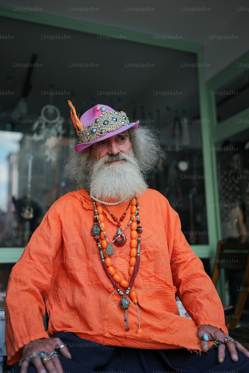 a man with a long beard wearing an orange shirt and a purple hat