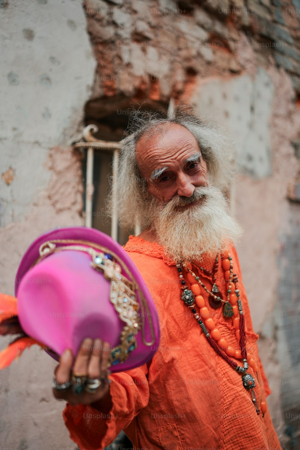 a man with a long white beard holding a pink hat