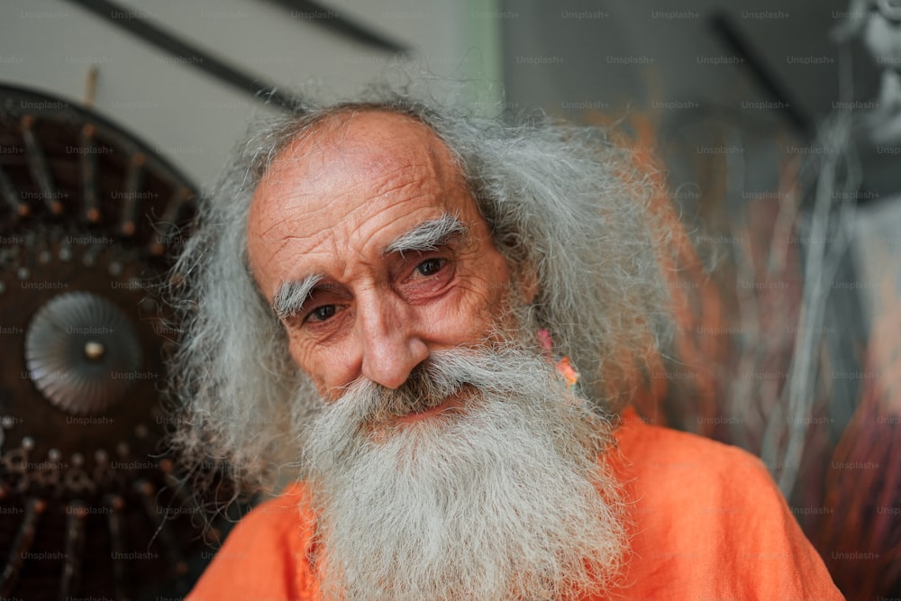 an old man with a long white beard wearing an orange shirt