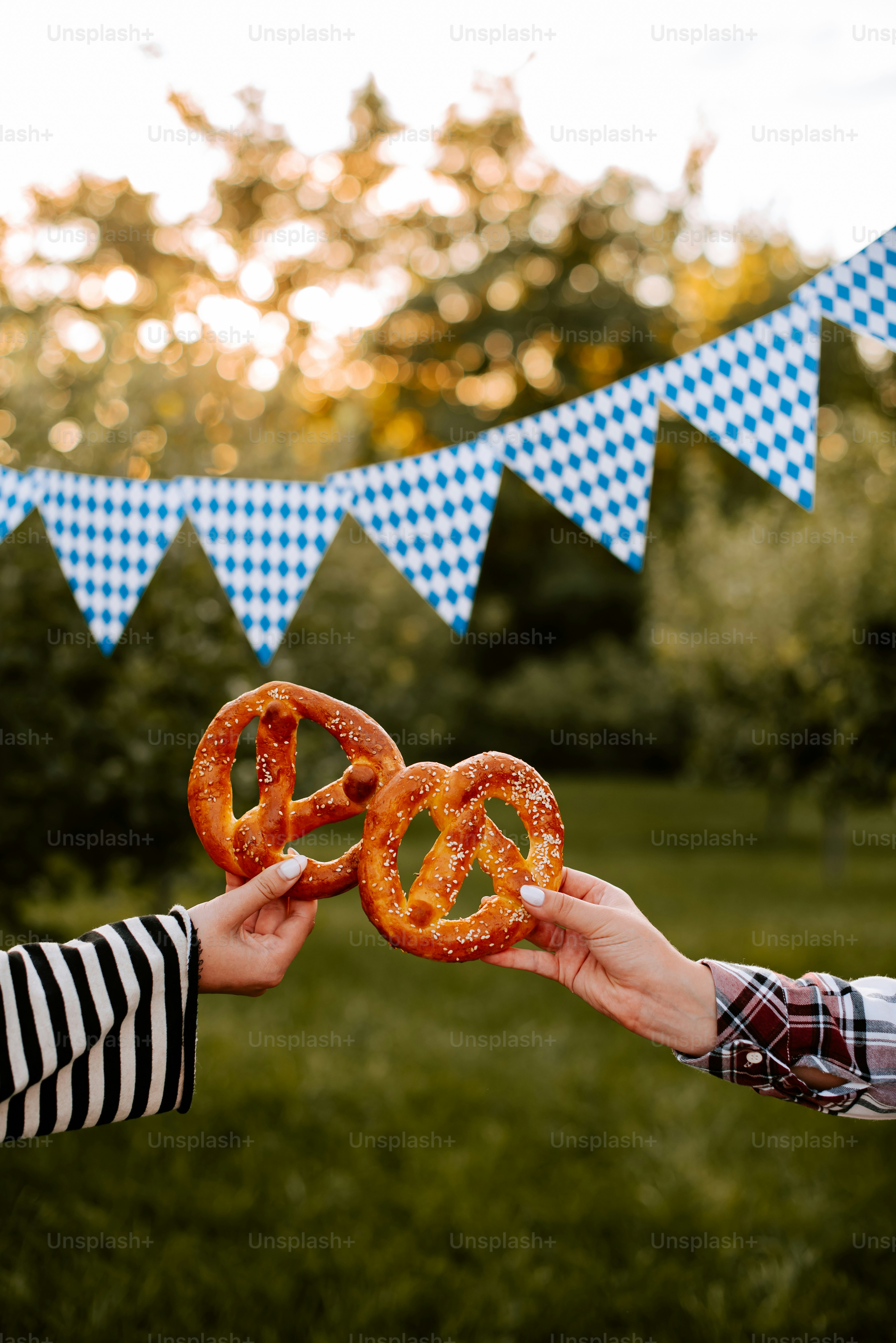two people holding up pretzels in front of a bunt banner