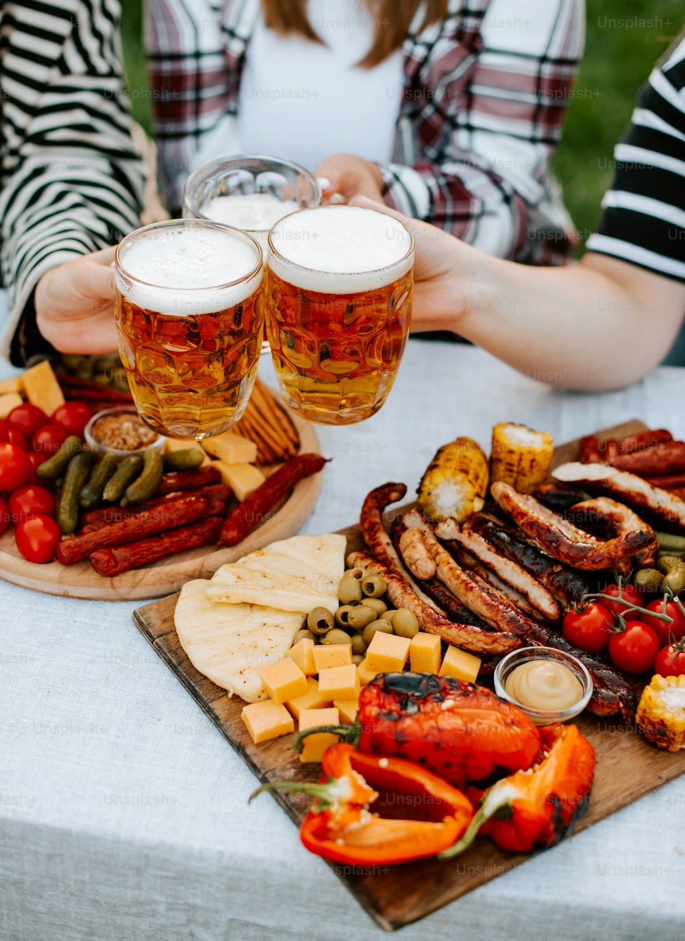 a table topped with two plates of food and two glasses of beer