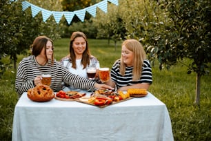 a group of women sitting around a table with food and drinks