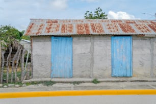 a run down building with blue shutters and a rusty roof