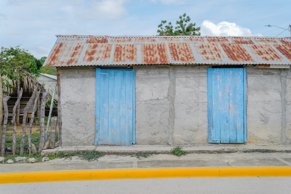 Un edificio deteriorado con persianas azules y un techo oxidado