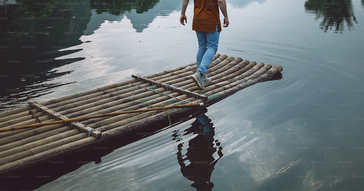 A man walking across a wooden raft across a river photo – Guangxi Image ...