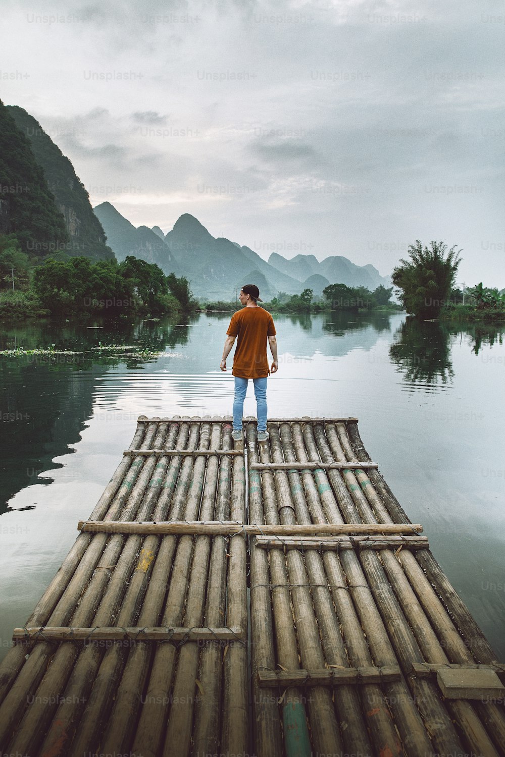 a person standing on a bamboo raft in the middle of a body of water