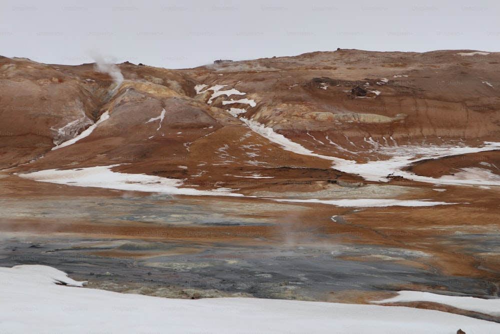 uma montanha coberta de neve ao lado de um corpo de água