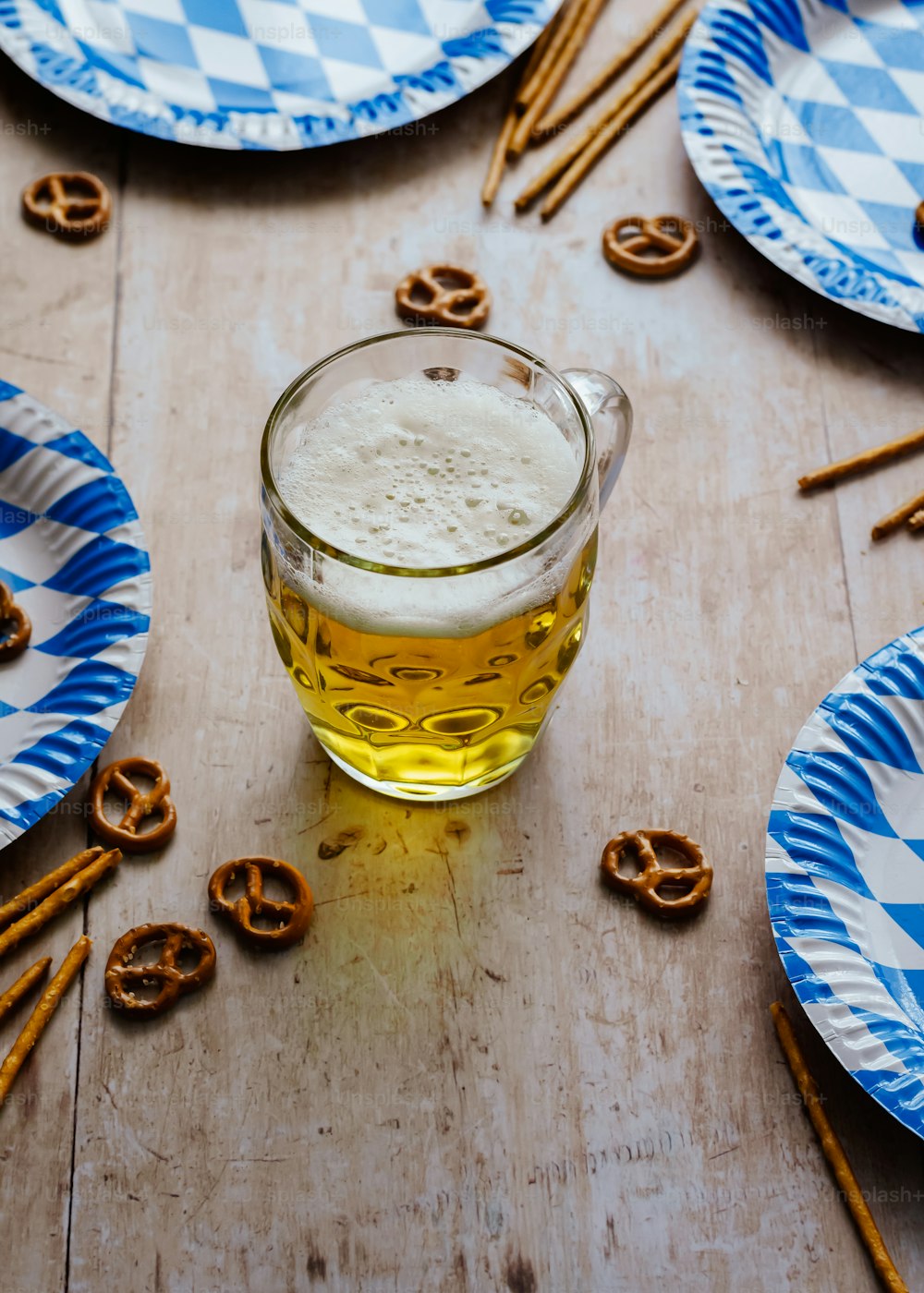 a cup of beer and some pretzels on a table