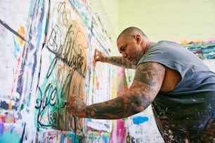Um homem está pintando grafite em uma parede