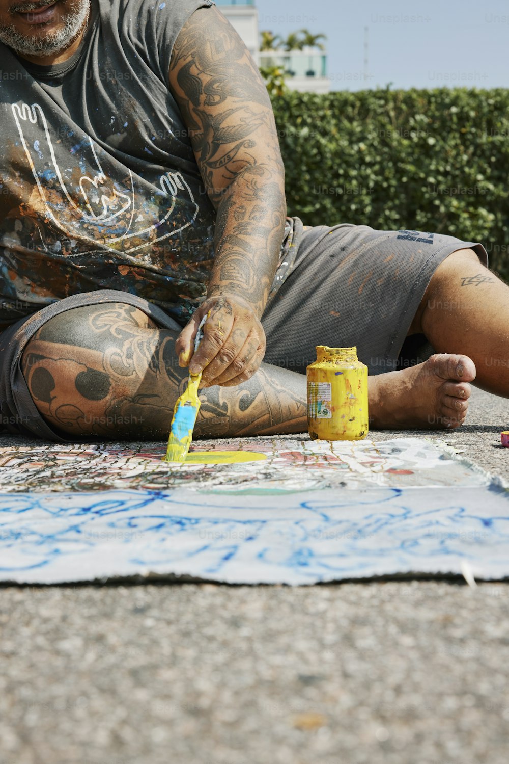 Un hombre sentado en el suelo pintando en el suelo
