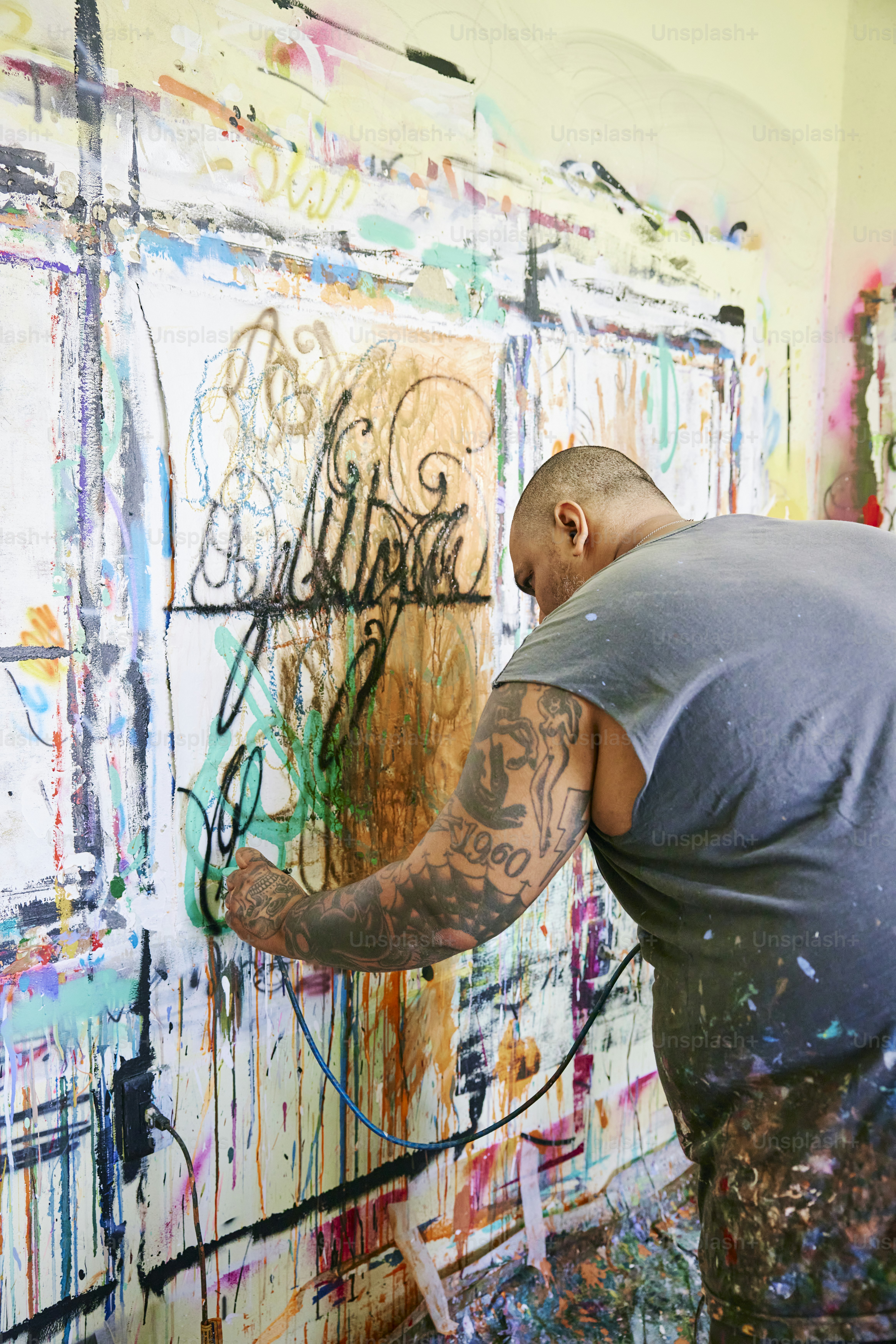 A man painting on a wall with lots of paint photo – Painter Image on ...
