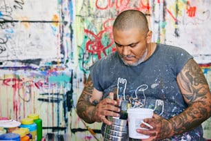 un hombre sosteniendo un cubo de pintura y un pincel