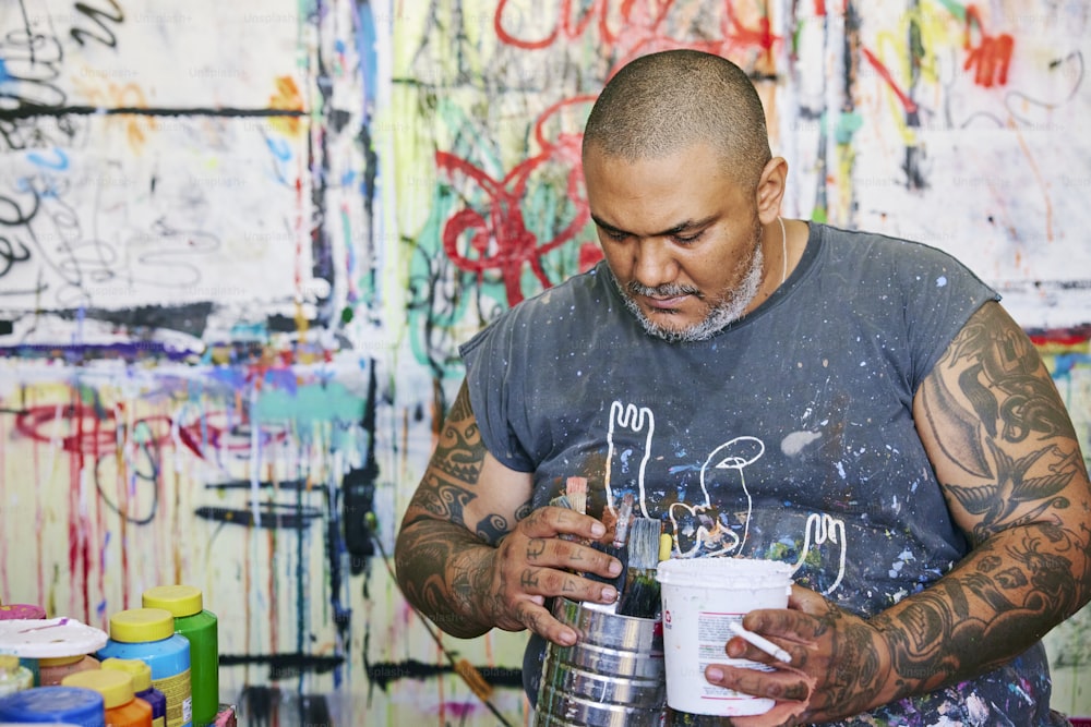 a man holding a bucket of paint and a paintbrush