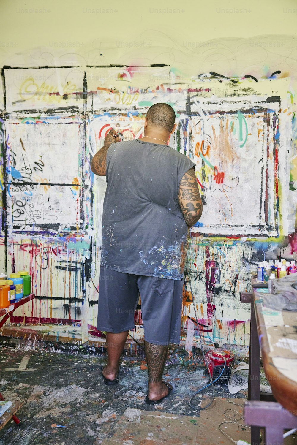 um homem pintando em uma parede coberta de grafite