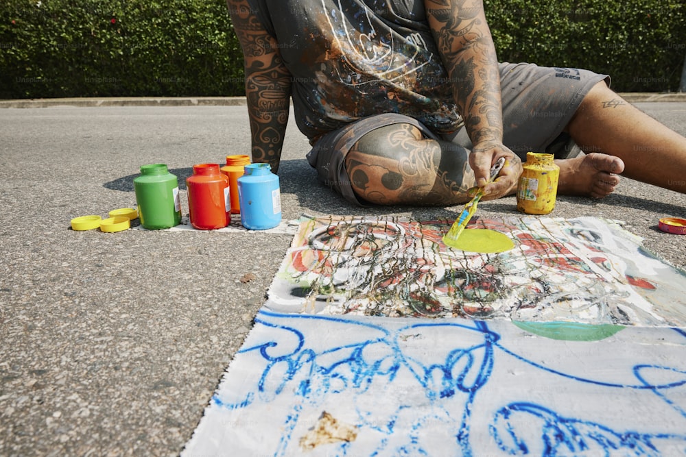 Ein Mann, der auf dem Boden sitzt und auf einem Blatt Papier malt