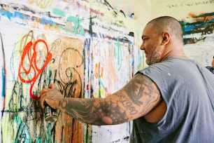 a man writing on a wall covered in graffiti