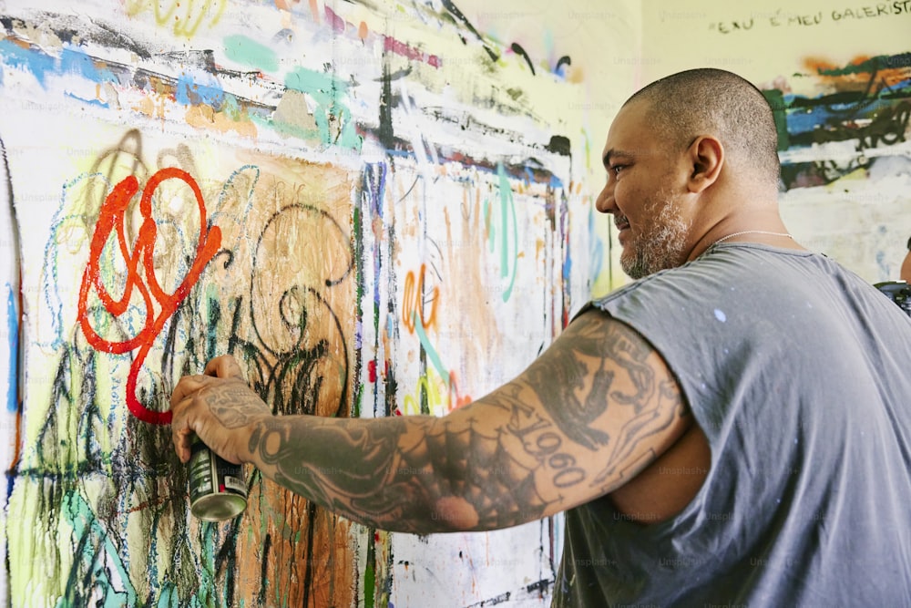 a man writing on a wall covered in graffiti