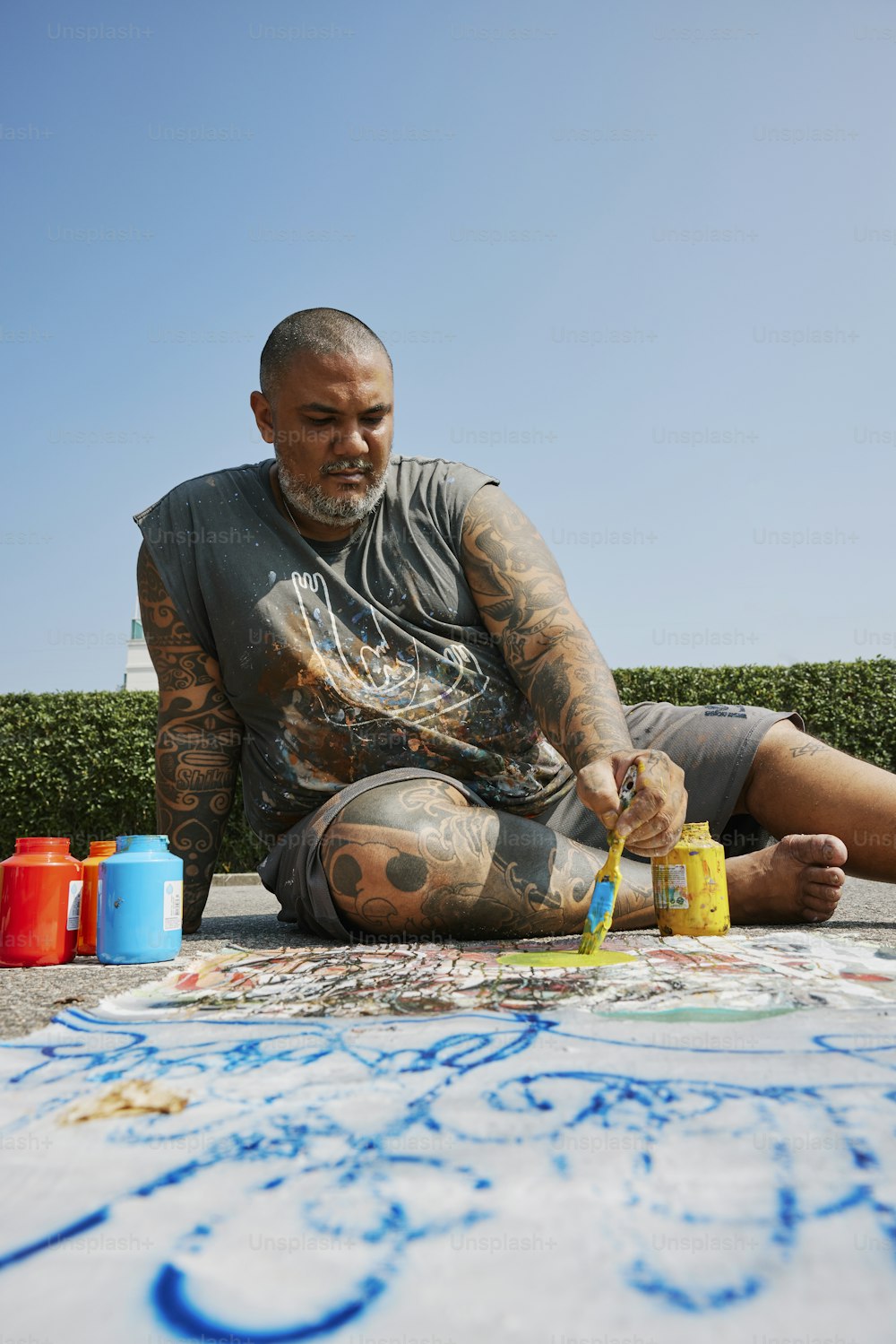 a man sitting on the ground painting on the ground