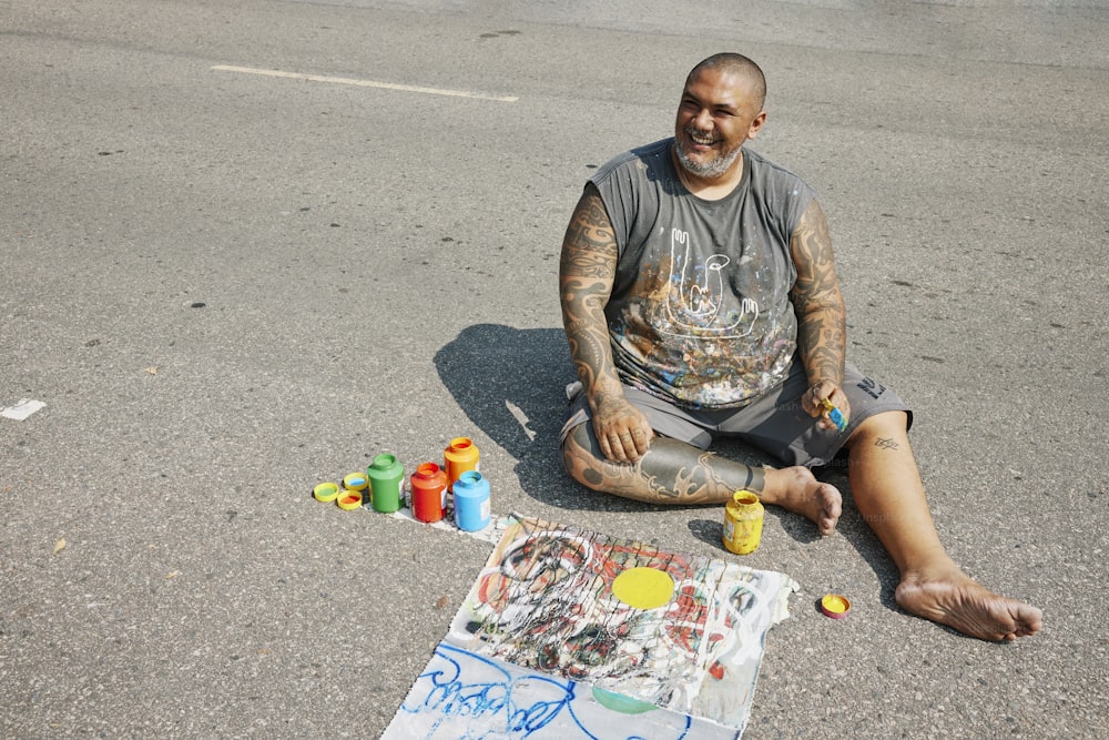 Un uomo seduto a terra accanto a un dipinto