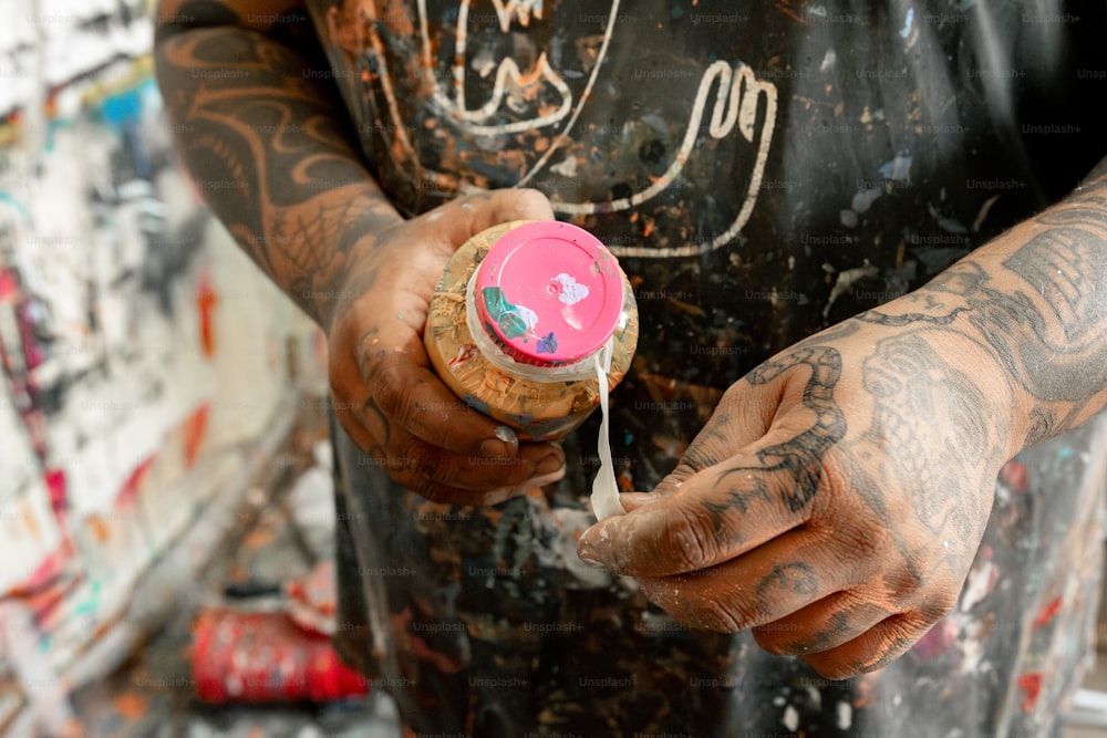 a tattooed man holding a bottle in his hands