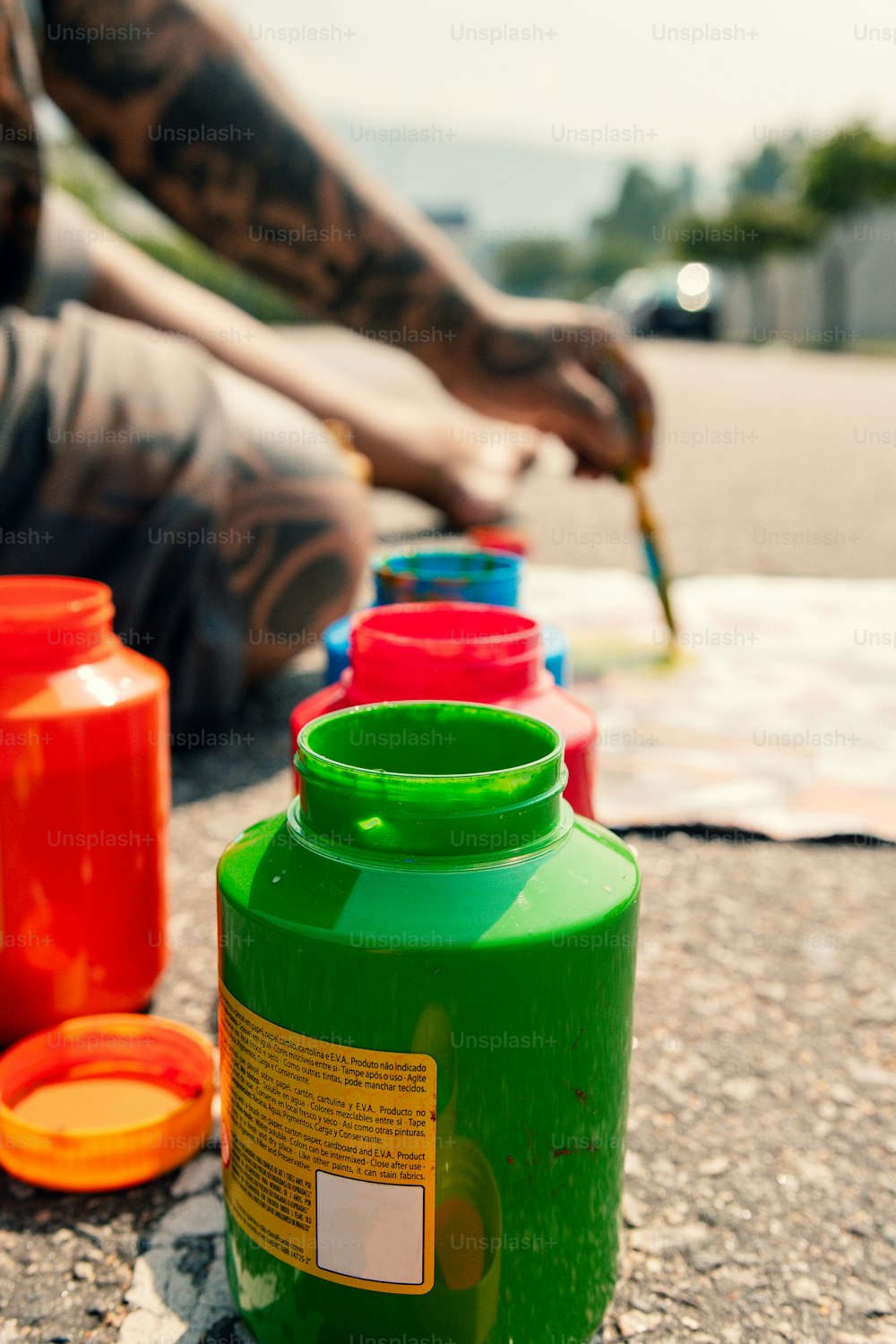 a man sitting on the ground next to a row of plastic jugs