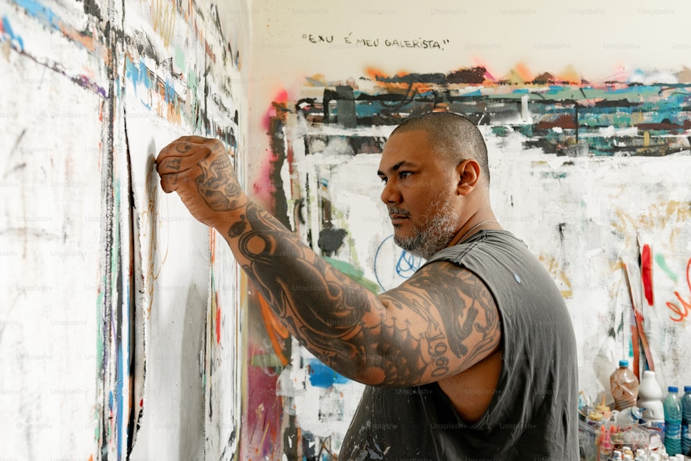a man is painting on a wall with lots of paint