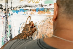 um homem escrevendo em uma parede com uma tesoura