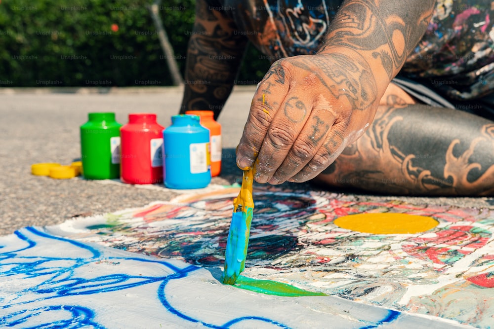 Un uomo con i tatuaggi sta dipingendo per terra