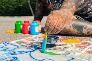 a man with tattoos is painting on the ground