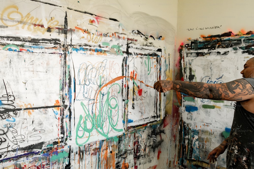 um homem pintando em uma parede com muitos grafites