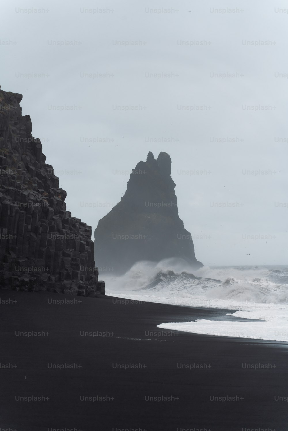 a black sand beach with a rock formation in the background